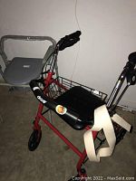 Red Drive brand rolling walker with four wheels and front basket shown on concrete floor.