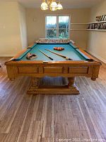 Front view of entire pool table with accessories on playing surface
