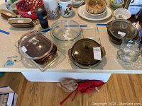 Clear and colored Pyrex bowls, lids, and clear rectangular glass dish on kitchen counter.