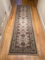Photo showing the full length of the Ariana polypropylene hallway rug laid on hardwood flooring, capturing the detailed floral and border pattern.