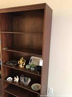Overview of large wooden shelf unit with six shelves and some decorative items placed on the shelves for scale.