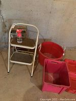 Two-step metal stool with wooden seat, large red plastic tub, and rectangular red storage bin seen from front angle