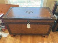 Front view of the wooden trunk showing metal stud details, key lock, and overall shape.