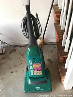 Front view of the green Sharp Twin Energy vacuum cleaner upright with power cord neatly wrapped around handle base.