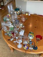Photo showing a variety of wine glasses in clear, colored, and floral patterns on a wooden table