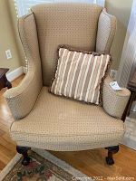 Front view of upholstered wing back chair with striped cushion, showing fabric wear and staining.