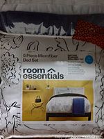 Packaged 5-piece microfiber bed set by Room Essentials showing front of packaging and bedding image.