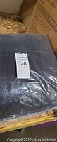 King size black blanket in original sealed packaging with a lot tag visible.