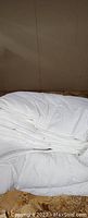 White thick cotton down comforter folded, showing soft and fluffy texture in new condition.