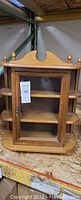 Front view of mini wooden curio cabinet with glass door, two shelves inside and decorative top finials.