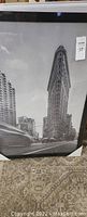 Framed black and white picture showing the Flatiron Building in NYC with a sticker tag attached.