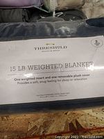 Photo of packaging label displaying product details: Threshold 15 lb weighted blanket, two-piece set with weighted insert and removable plush cover, dimensions 55 x 80 inches.