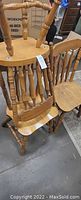 Photo showing three wooden chairs, spindle back design, light finish, used condition.