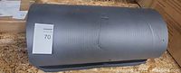 Photo of a rolled-up black yoga or camping mat on a countertop with a lot number tag attached.