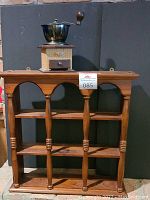 Front view of wooden curio shelf with three vertical carved posts and three shelves.