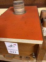 Bench mount drum sander with orange top and cylindrical sanding drum mounted.