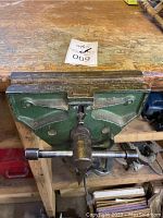 Top view of Grizzly quick acting woodworking bench vise mounted on a workbench showing the steel jaws and main central screw handle.