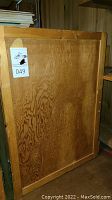 Photo of the wooden storage box side showing wood grain and auction lot sticker