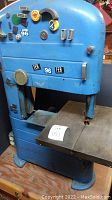 Front and side views of blue Craftsman band saw with metal cutting table and control panel, showing wear and decals with date stamps.