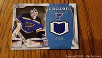 Front side of the collectible card featuring Brian Elliott in his goalie uniform and the embedded piece of game-used jersey.