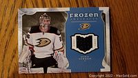 Front of the hockey card showing John Gibson in Anaheim Ducks goalie gear with embedded black fabric piece.