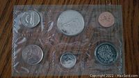 Photo of 7 Canadian coins sealed in plastic, showing various denominations and designs including maple leaf and Queen Elizabeth II profile.