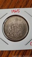 Reverse side of the coin showing the Canadian coat of arms with a crown and heraldic figures, the denomination and the date 1965.