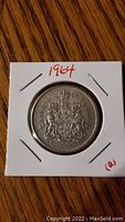 Front side of the 1964 Canadian 50 cent silver coin showing Canadian coat of arms and date.