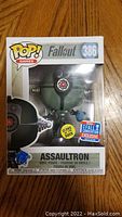 Photo of Funko Pop Assaultron figure in original box showing 2018 Fall Convention Exclusive sticker and glow in the dark feature.