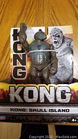 Front view of Kong: Skull Island action figure in packaging on a wooden surface.