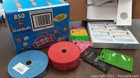 Photo of two rolls of vending tickets (red and blue), assorted colored window bags, and a cash register drawer with paper bills and coins.