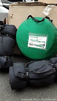 Two black inflatable camping mats rolled and folded next to a green circular carrying case for the foldable pop-up tent.