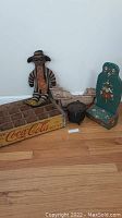 Lot showing Coca-Cola wooden crate, doll figure, ship decoration, cast iron pot, and decorative chair.