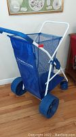 Full side view of the blue Nantucket Beach Buggy showing the padding handlebar, mesh side panel, large fat rear wheels and white metal frame.