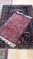 Both scatter rugs stacked, small red floral rug on top of large navy floral rug