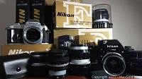 Overall view of two Nikon camera bodies, multiple lenses, Nikon boxes and accessories