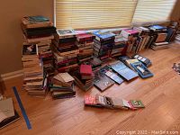 Multiple large stacks of books on the floor, showing the entire collection's scale and condition.
