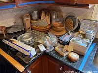 Overview photo of various bakeware and kitchen items including cast iron pans, tartlet molds, metal pizza slice holders, wooden bowls, woven baskets, and aluminum pans.