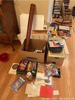 Overview of craft supplies including paper stacks, rolled vinyl fabric, pencils, and various boxed items on the floor