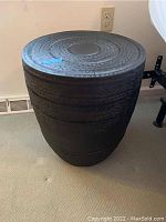 Full view of the textured metal stand placed on carpeted floor next to wall outlet.