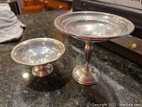Two sterling silver footed bowls displayed on a dark granite surface, showing their shape and finish.