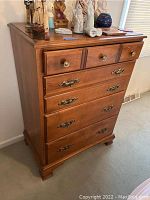 Front view of the Van Stee wooden chest of drawers with brass hardware and wooden knobs showing overall condition and design.