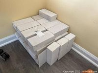 Stack of 36 solid white rectangular bricks arranged in rows against wall on floor.