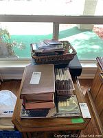 Photo of a stack of religious books, CDs in cases, and wicker baskets on a table.