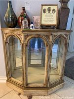 Front view of wooden display cabinet showing glass shelves and decorative carved arches.