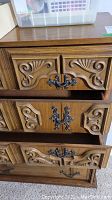 Close-up of three of the dresser drawers showcasing carved wooden detail and dark metal handles.