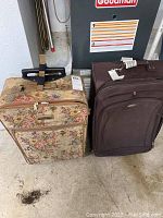 Two suitcases on floor, left one floral patterned Vanderbilt Studio carry-on, right one brown suitcase with wheels