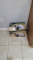Photo of new unopened LEM 7.5 inch meat slicer box placed on a tiled floor near a wall.