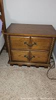 Full front view of the wooden nightstand showing two drawers with metal handles and decorative carved trim.