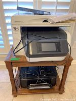 Photo of HP OfficeJet Pro 8710 printer on wooden side table with papers and cables visible